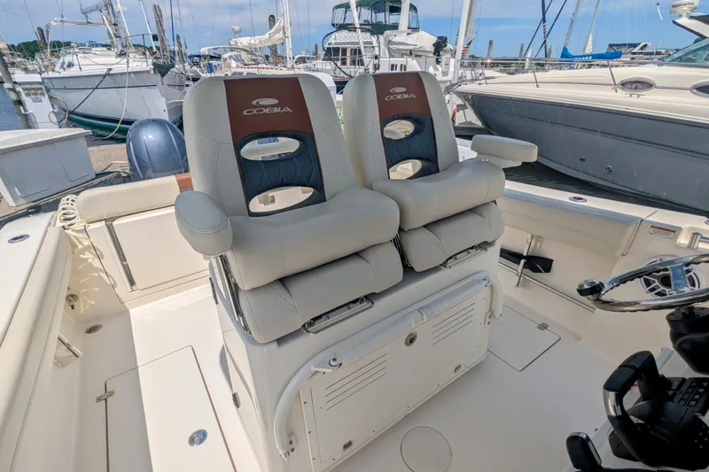  Yacht Photos Pics 2023 Cobia 280 Center Console boat interior with dual captain's chairs at a marina.