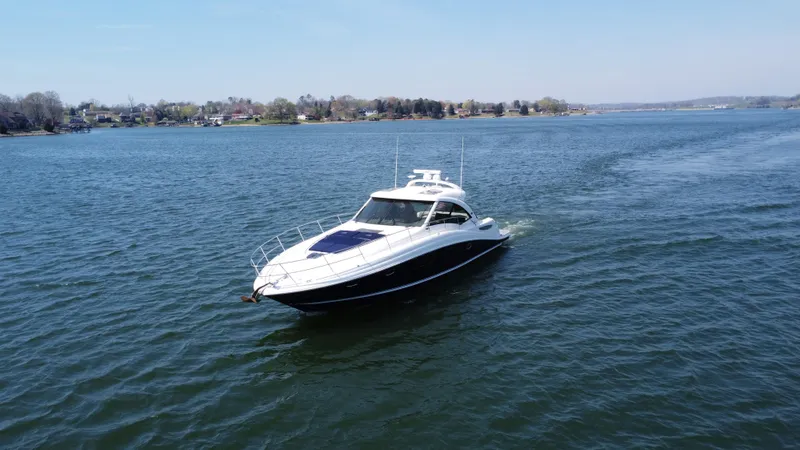  Yacht Photos Pics 2006 Sea Ray 48 Sundancer yacht cruising on a calm lake under a clear blue sky.