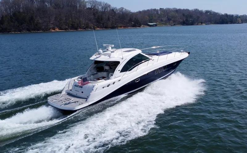  Yacht Photos Pics 2006 Sea Ray 48 Sundancer cruising on a serene lake with wooded shoreline.