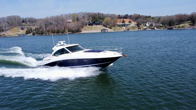  Yacht Photos Pics 2006 Sea Ray 48 Sundancer cruising on a scenic lake with shoreline in the background.