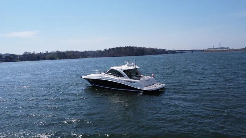 Yacht Photos Pics 2006 Sea Ray 48 Sundancer yacht cruising on a serene lake under a clear blue sky.