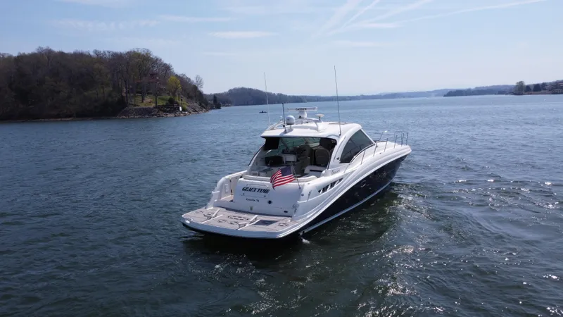  Yacht Photos Pics 2006 Sea Ray 48 Sundancer yacht cruising on a serene lake with scenic shoreline.