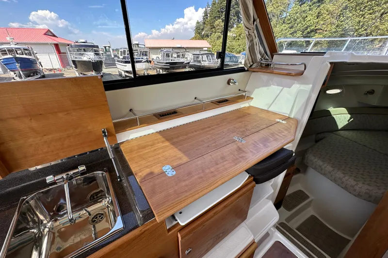  Yacht Photos Pics Interior of 2026 Cutwater C-32 C boat with wooden table and compact kitchen area.