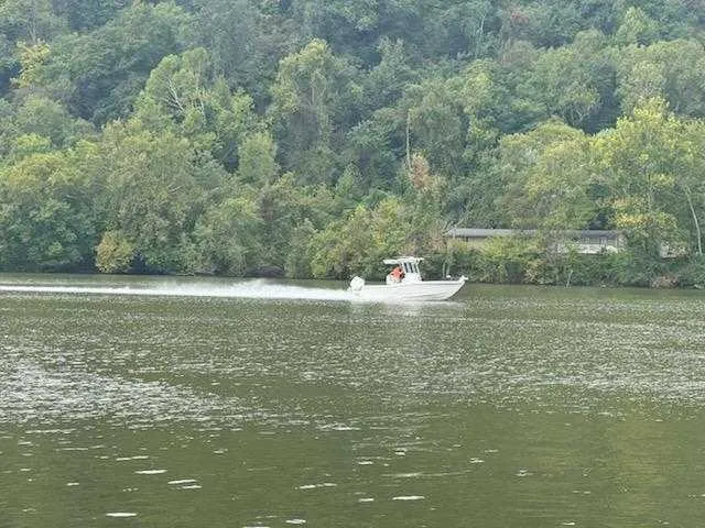 Hybrid Performance Yacht Photos Pics 2025 Caymas 24 HB boat cruising on a scenic, tree-lined river.