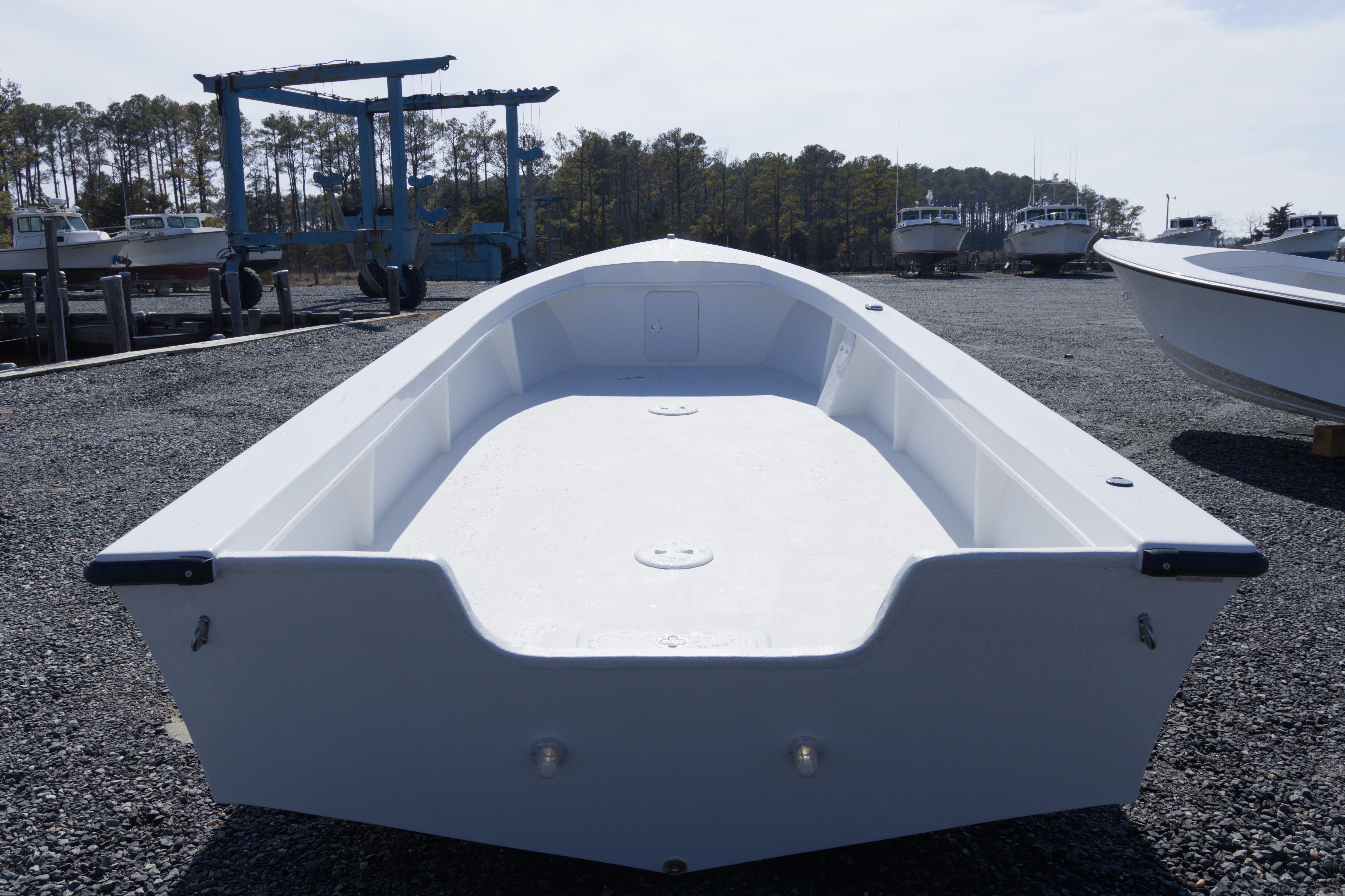 2026 C-Hawk 20 Commercial boat on gravel lot, surrounded by trees and other boats.
