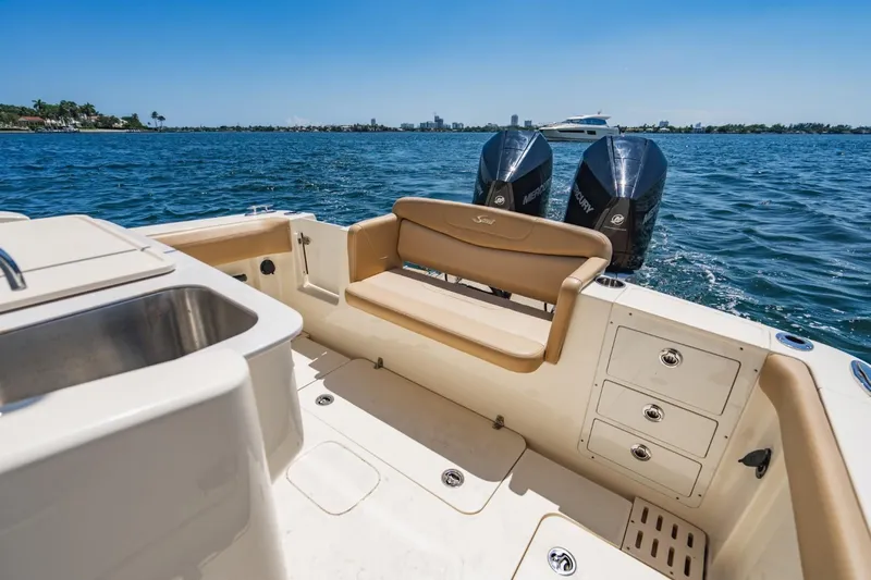  Yacht Photos Pics 2022 Scout 305 LXF boat interior with seating, sink, and dual Mercury engines on water.