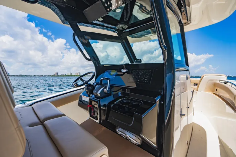  Yacht Photos Pics 2022 Scout 305 LXF boat interior with steering console, ocean view, and clear sky.
