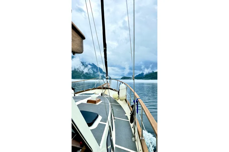  Yacht Photos Pics 1980 Nauticat Pilothouse sailing on a serene lake with misty mountains.