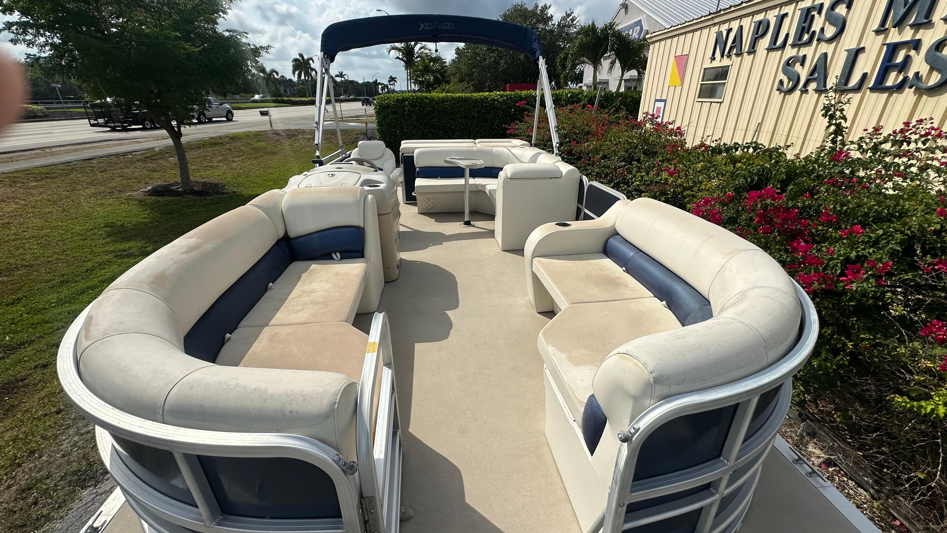 2012 Xcursion X21C pontoon boat with spacious seating, displayed at a sales location.