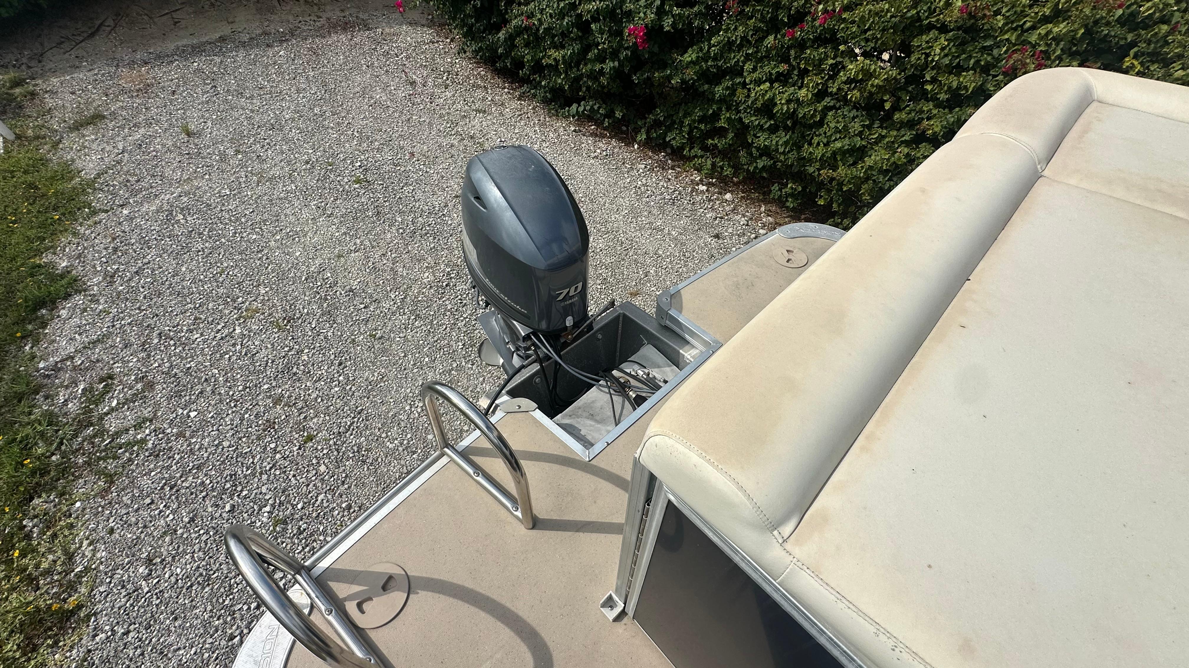 2012 Xcursion X21C boat with outboard motor and seating, parked on gravel.