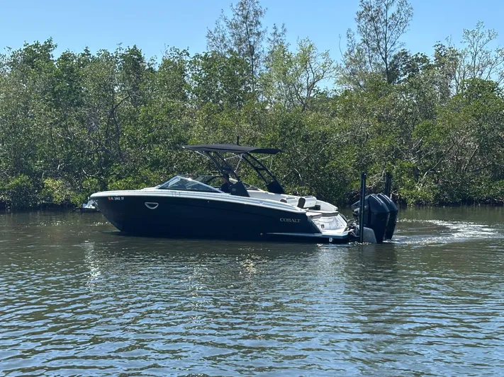  Yacht Photos Pics 2022 Cobalt R8 Outboard boat cruising on a calm river with lush greenery.