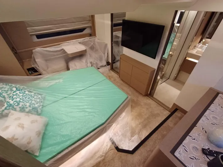  Yacht Photos Pics Luxurious Prestige 590 yacht bedroom interior, 2020 model, featuring a bed, TV, and modern decor.