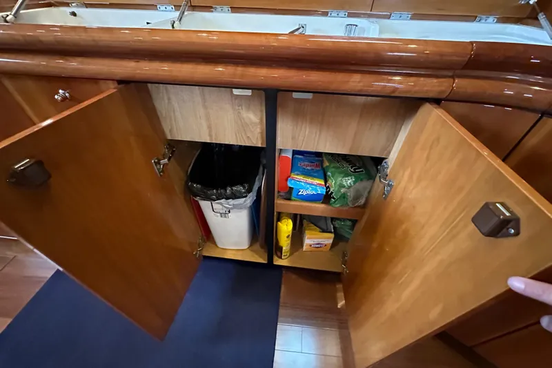 D Yacht Photos Pics Open wooden cabinets in Sunseeker Predator 60 yacht kitchen, showcasing storage space and supplies.