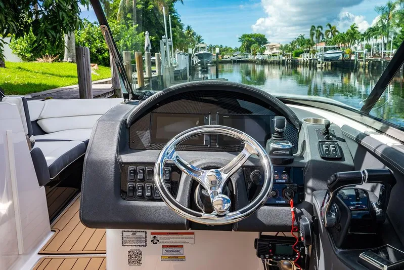 Dreamaker Yacht Photos Pics 2021 Regal 29 OBX boat cockpit with steering wheel, controls, and scenic canal view.