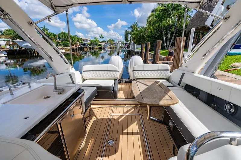 Dreamaker Yacht Photos Pics Luxurious 2021 Regal 29 OBX boat interior with seating, table, and sink by a scenic canal.