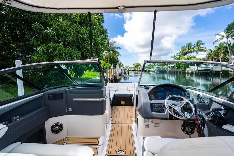 Dreamaker Yacht Photos Pics 2021 Regal 29 OBX boat interior with steering wheel, dockside view, and lush greenery.