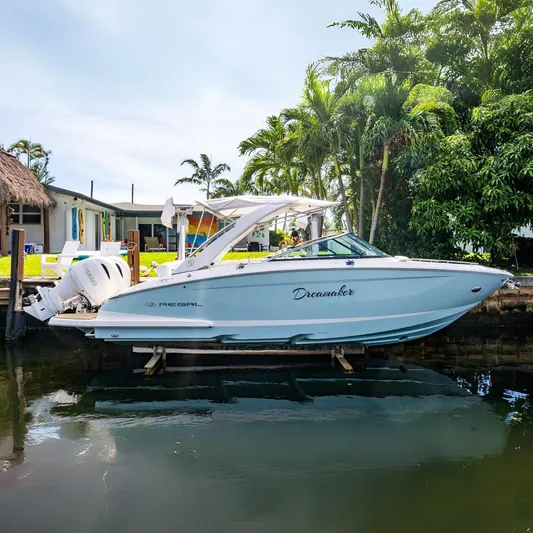 Dreamaker Yacht Photos Pics 2021 Regal 29 OBX boat docked by a tropical waterfront home.
