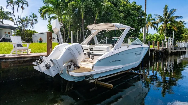 Dreamaker Yacht Photos Pics 2021 Regal 29 OBX boat docked by tropical waterfront with lush greenery.