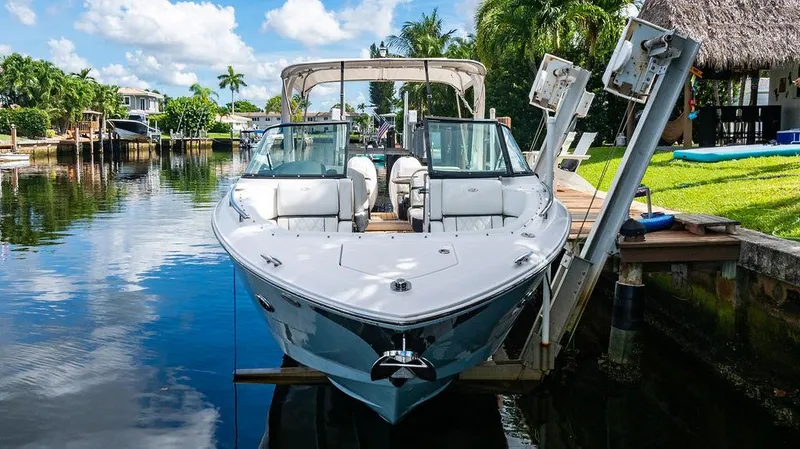 Dreamaker Yacht Photos Pics 2021 Regal 29 OBX boat docked by a scenic waterfront with lush greenery.