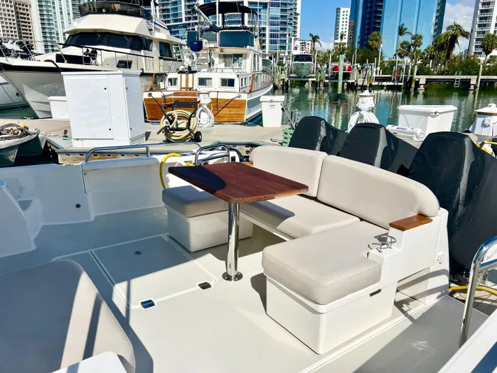 Risk & Reward Yacht Photos Pics 2022 Back Cove 39O yacht with seating area and table, docked in a marina.