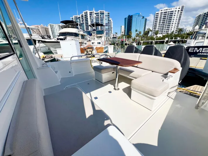 Risk & Reward Yacht Photos Pics 2022 Back Cove 39O yacht deck with seating, docked in a marina with cityscape background.