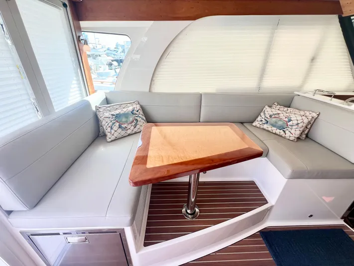 Risk & Reward Yacht Photos Pics 2022 Back Cove 39O interior with L-shaped seating and wooden table.