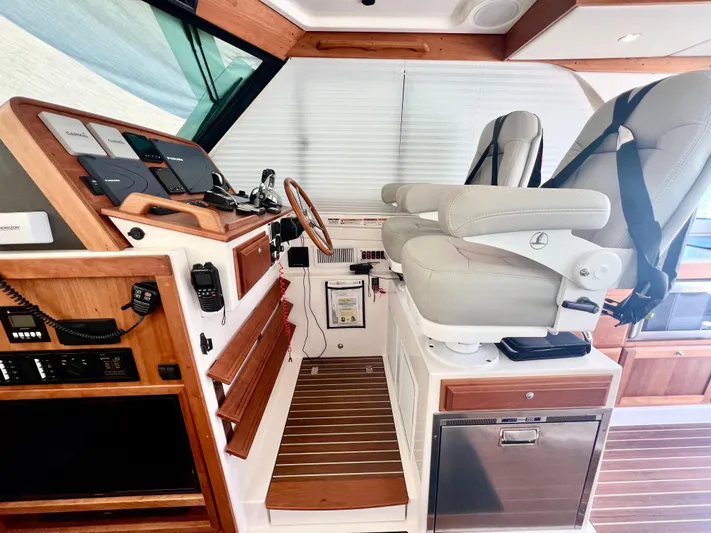 Risk & Reward Yacht Photos Pics 2022 Back Cove 39O helm with dual seats, wooden accents, and modern navigation equipment.