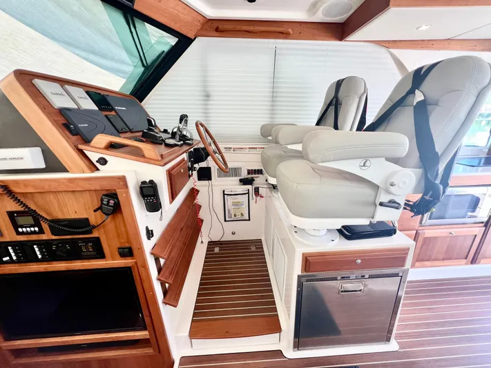 Risk & Reward Yacht Photos Pics 2022 Back Cove 39O helm with dual seats, wooden accents, and modern navigation equipment.