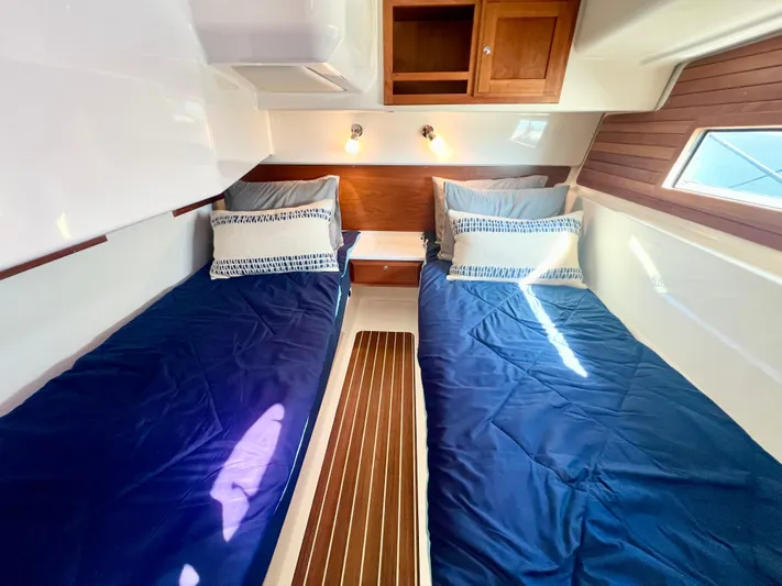 Risk & Reward Yacht Photos Pics 2022 Back Cove 39O cabin with twin beds, blue bedding, and wooden accents.