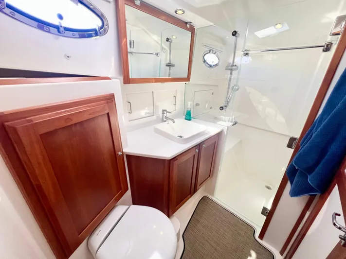 Risk & Reward Yacht Photos Pics Luxurious bathroom in 2022 Back Cove 39O yacht with wooden cabinetry and modern fixtures.