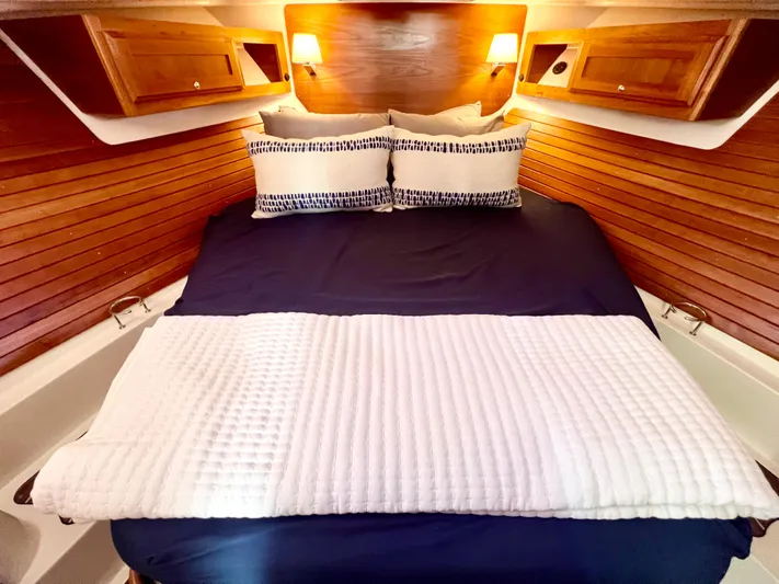 Risk & Reward Yacht Photos Pics Cozy cabin bedroom in 2022 Back Cove 39O yacht with wooden paneling and elegant bedding.