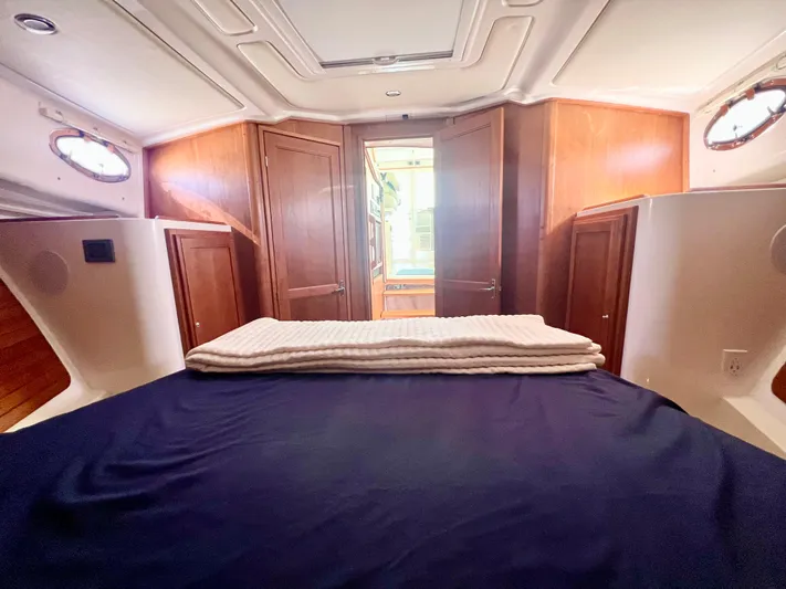 Risk & Reward Yacht Photos Pics 2022 Back Cove 39O cabin interior with bed, wooden cabinets, and portholes.