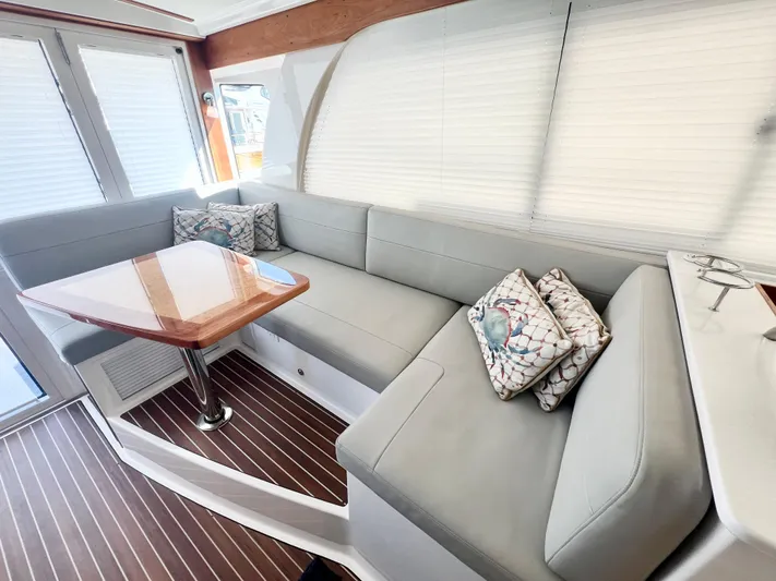 Risk & Reward Yacht Photos Pics 2022 Back Cove 39O interior with gray seating, wooden table, and decorative pillows.