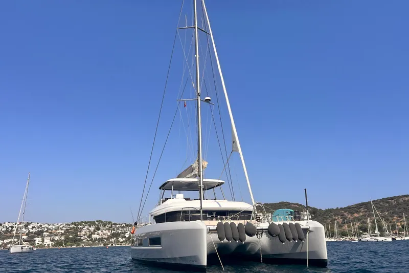 Nani Yacht Photos Pics 2024 Lagoon 55 catamaran anchored in a scenic bay with clear blue skies.