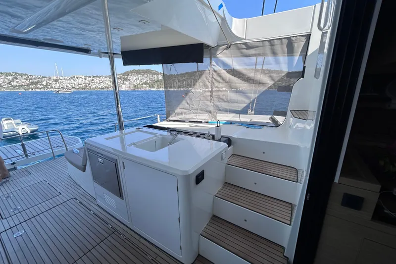 Nani Yacht Photos Pics 2024 Lagoon 55 yacht deck with outdoor kitchen, overlooking serene blue waters.