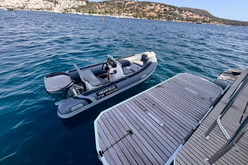 Nani Yacht Photos Pics Inflatable boat beside 2024 Lagoon 55 yacht on calm blue water.