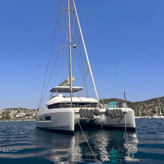 Nani Yacht Photos Pics 2024 Lagoon 55 catamaran anchored in a scenic bay with clear blue skies.