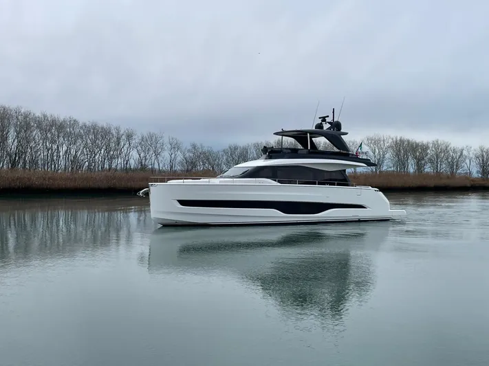  Yacht Photos Pics 2025 Cranchi 62 Sessantadue yacht on calm water, surrounded by trees.