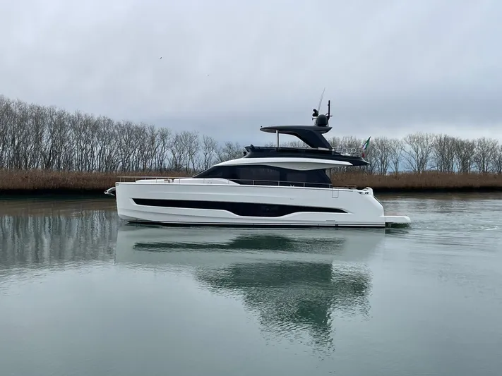  Yacht Photos Pics 2025 Cranchi 62 Sessantadue yacht on calm water, surrounded by bare trees.