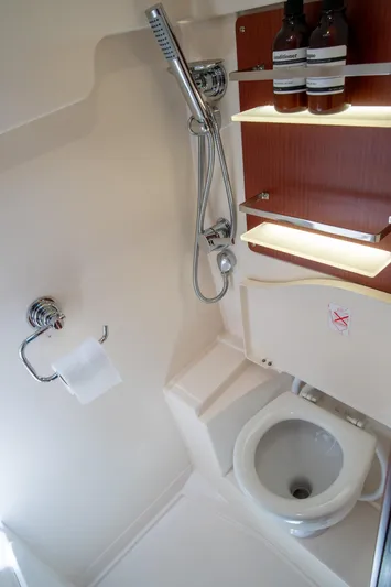Anthem Yacht Photos Pics 2022 Dehler 34 yacht bathroom with shower, toilet, and wooden shelving.