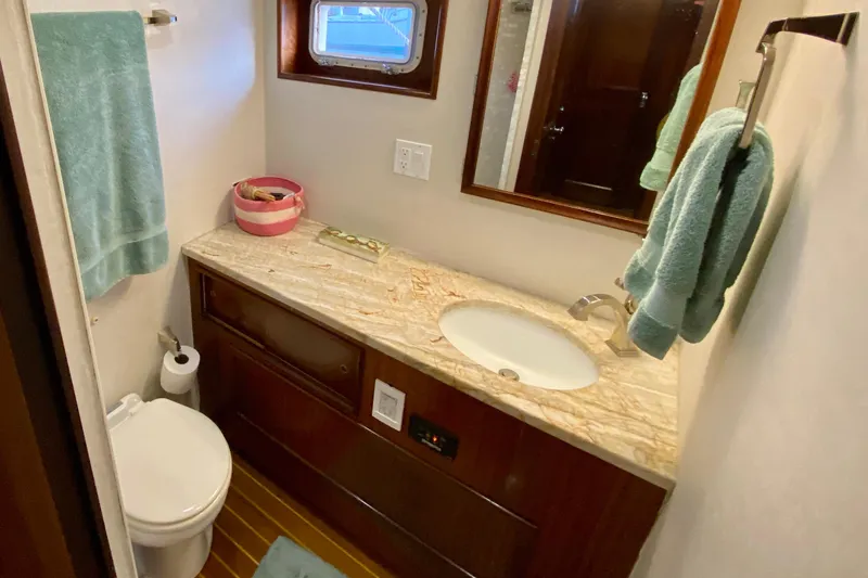 Lazy Livin' Yacht Photos Pics Bathroom interior of 1971 Hatteras 43 Double Cabin with marble countertop and wooden cabinetry.
