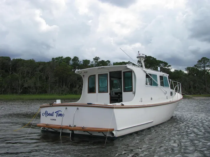 About Time Yacht Photos Pics 1998 Duffy 35 Downeast Cruiser on calm water, cloudy sky backdrop.