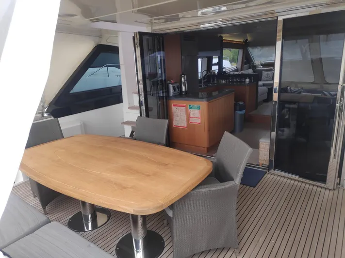  Yacht Photos Pics Outdoor dining area on 2013 Monte Carlo Yachts MCY 65, featuring a wooden table and chairs.