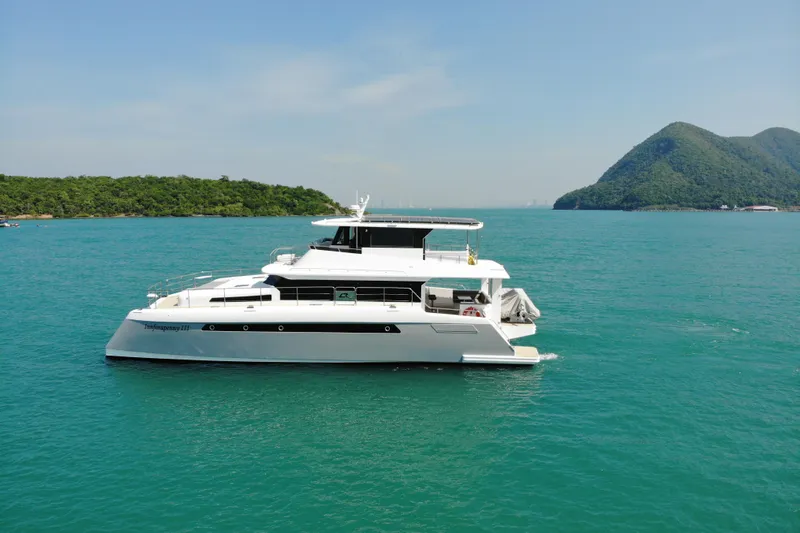Innforapenny III Yacht Photos Pics 2020 PowerPlay Catamarans Longreach 1900 Expedition on turquoise water with scenic island backdrop.