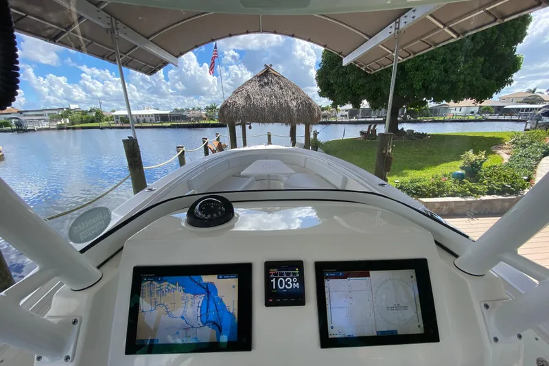 Pretty Fine Yacht Photos Pics Edgewater 320CC boat dashboard with navigation screens, docked by a scenic waterfront.