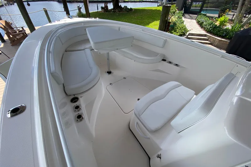 Pretty Fine Yacht Photos Pics 2015 Edgewater 320CC boat interior with white seating and table, docked by a waterfront.