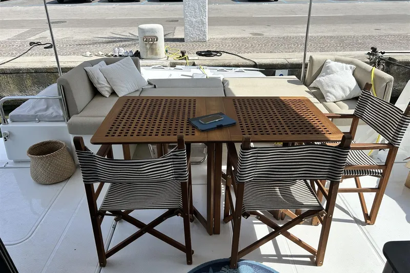  Yacht Photos Pics 2025 Fountaine Pajot MY4.S yacht deck with wooden table, striped chairs, and cozy seating.