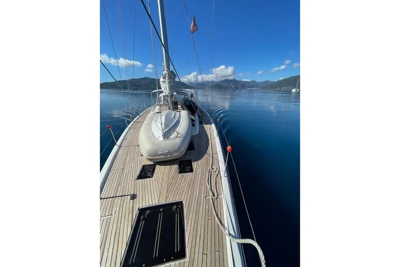  Yacht Photos Pics 2015 Dufour 560 Grand Large yacht on calm waters, clear sky, scenic mountain backdrop.