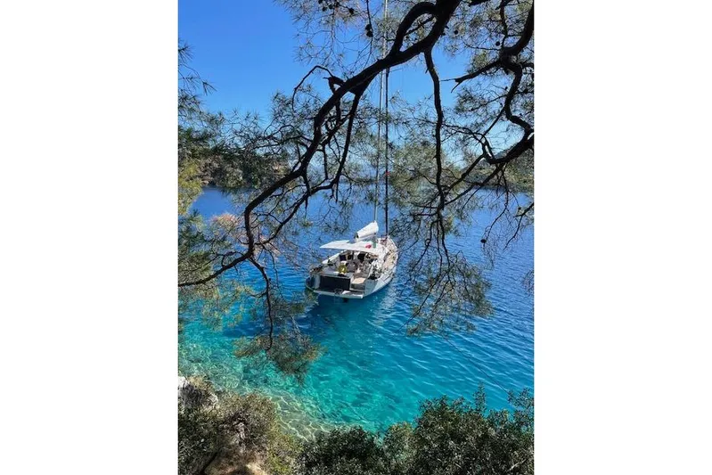  Yacht Photos Pics Sailboat Dufour 560 Grand Large 2015 anchored in clear blue waters, surrounded by trees.