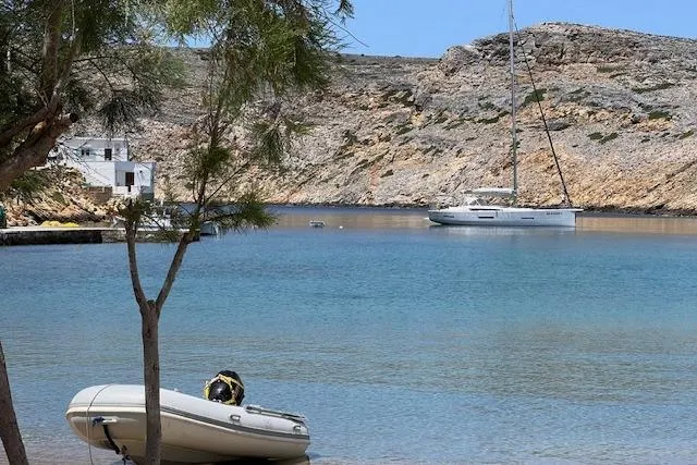  Yacht Photos Pics Sailboat Dufour 560 Grand Large 2015 anchored in a serene coastal bay.